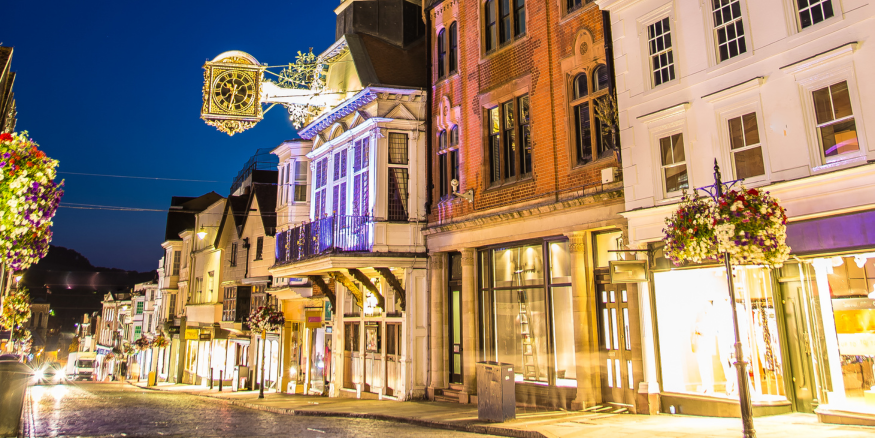 Photo of the town center of Guildford in Surrey at night, where we can see the front of traditional buildings in the Main Street.